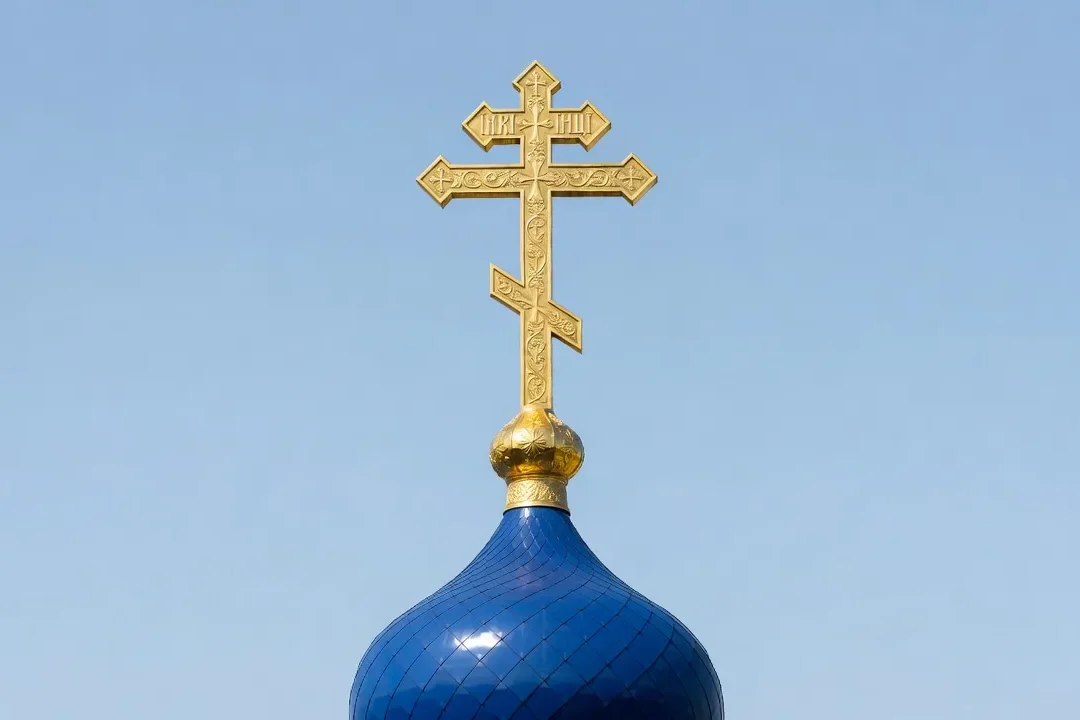 Croix orthodoxe dorée à trois barres au sommet d'une coupole en bulbe, ciel bleu
